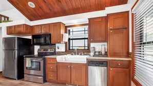 A modern kitchen with wooden cabinets, stainless steel appliances, and a large window. - Charming Tiny House Near Lake & Springs (Lampasas)