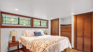 A bedroom with a bed, nightstands, a wooden wardrobe, and a window with blinds. - Charming Tiny House Near Lake & Springs (Lampasas)