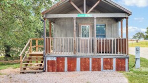 A rustic wooden cabin with a porch, a staircase, and a sign reading "Tumble on INN". - Charming Tiny House Near Lake & Springs (Lampasas)