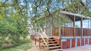 A wooden staircase leading to a covered outdoor area with a metal fence and a sign reading "Tumble on." - Charming Tiny House Near Lake & Springs (Lampasas)