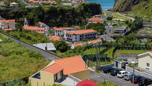 A coastal town with buildings, a road, and a red location marker. - Pereira Place Cottage (São Vicente)