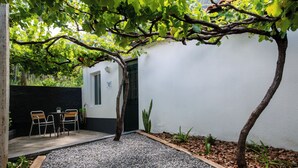 A small patio with a table and chairs, surrounded by gravel and plants. - Pereira Place Cottage (São Vicente)