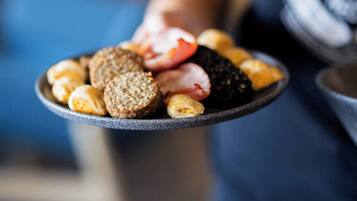 Une personne tenant une assiette contenant divers aliments, notamment du pain, des tomates et des olives.