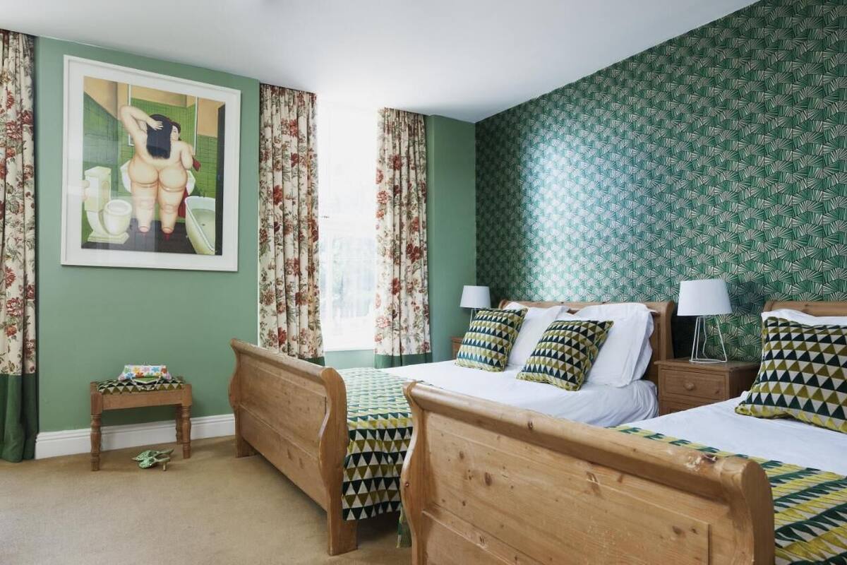 A bedroom with two wooden beds, a small table, and a painting on the wall.