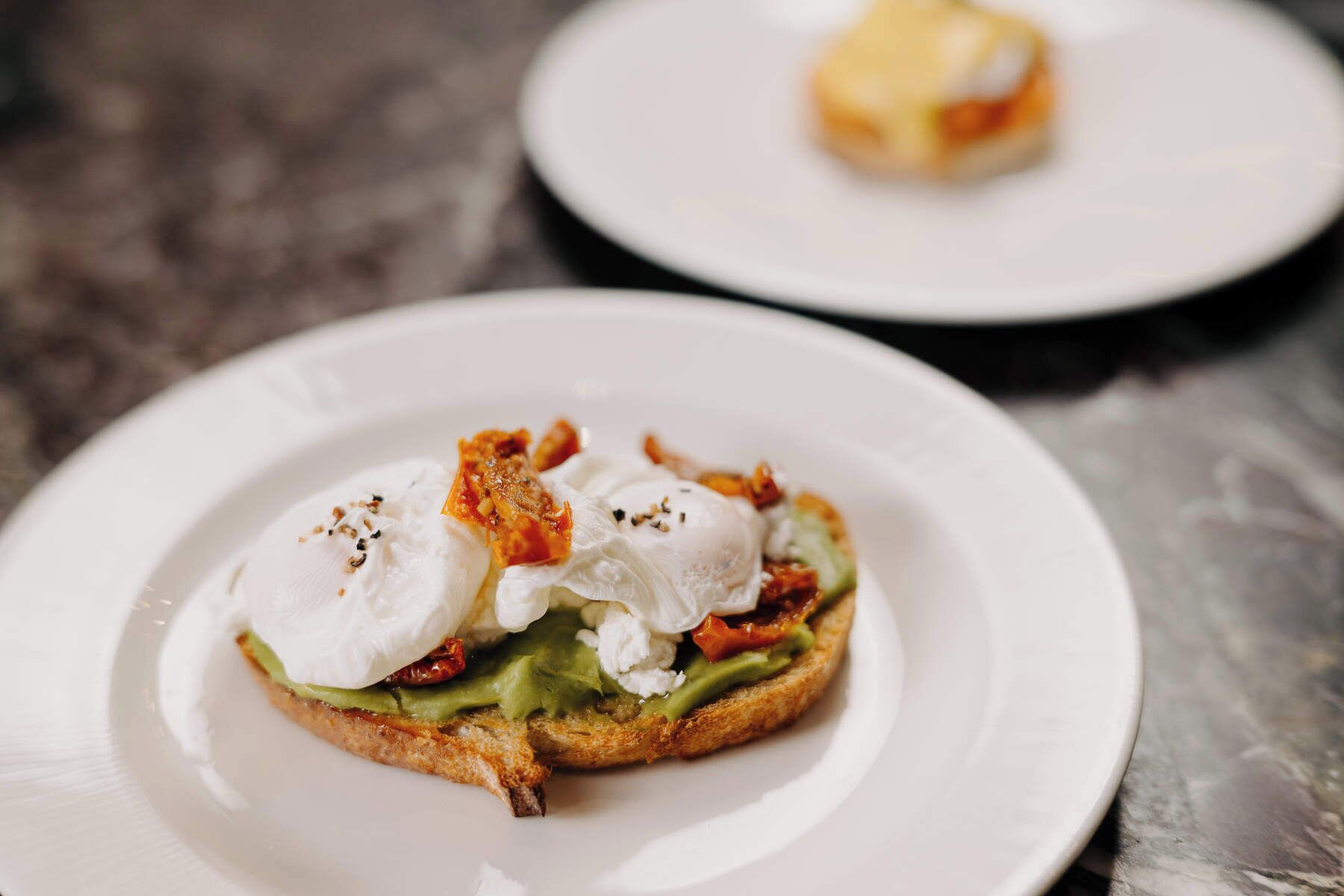 A breakfast dish with poached eggs, avocado, and bacon on toast.