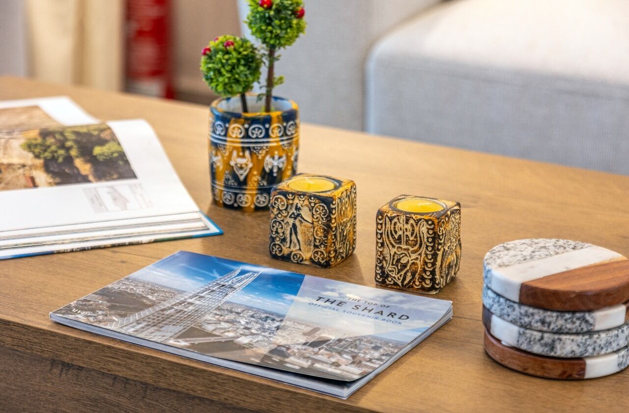 A table with a decorative vase, candle holders, a souvenir book, and coasters.