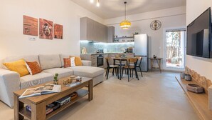 A modern living room with a sofa, coffee table, and dining area. - Petra - Stylish Apartment (Hersonissos)