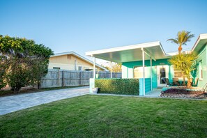 Ein zweigeschossiges Haus mit einer überdachten Terrasse, einem eingezäunten Garten und einem gepflegten Rasen.