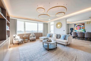 A modern living room with a sofa, armchairs, a coffee table, and a dining area with chairs and a table.