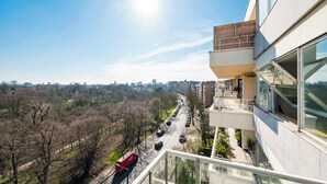 Un edifici alt amb un balcó que dona a una vista de la ciutat i un carrer arbrat.