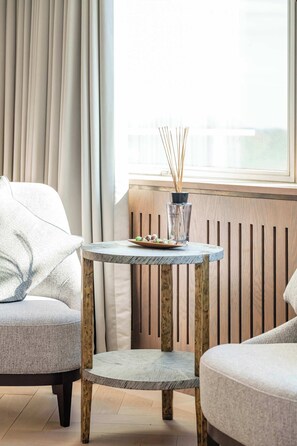 Ein modernes Wohnzimmer mit rundem Tisch, einer Couch und einem Fenster mit Vorhängen.