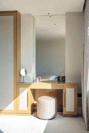 A modern bedroom with a wooden desk, a round mirror, and a bed with a headboard.