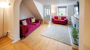 A spacious living area with two red sofas, a white rug, and a potted plant.
