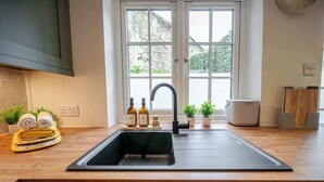 A modern kitchen with a large window, a black sink, and wooden countertops.