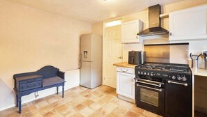 Una cocina compacta con estufa, horno, refrigerador y una pequeña mesa.