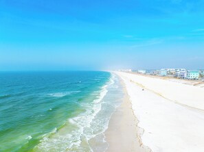 A beach with a clear view of the ocean and a row of buildings along the shore. - 🏝️Just Beachy🏝️ 3BR Townhome | Beachfront | Heart of Mexico Beach | (Mexico Beach)