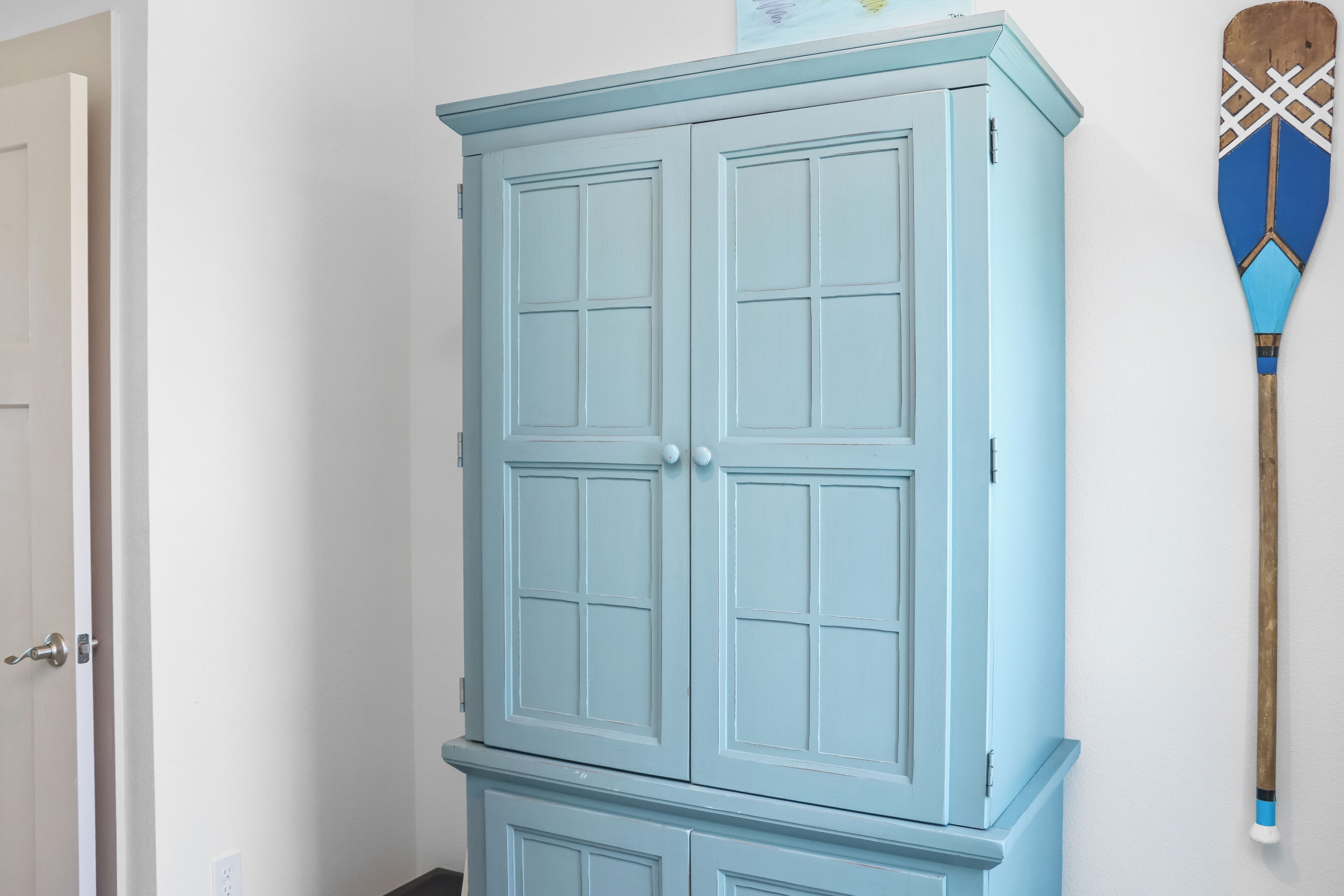 Un mueble azul claro con dos puertas y un armario más pequeño debajo.