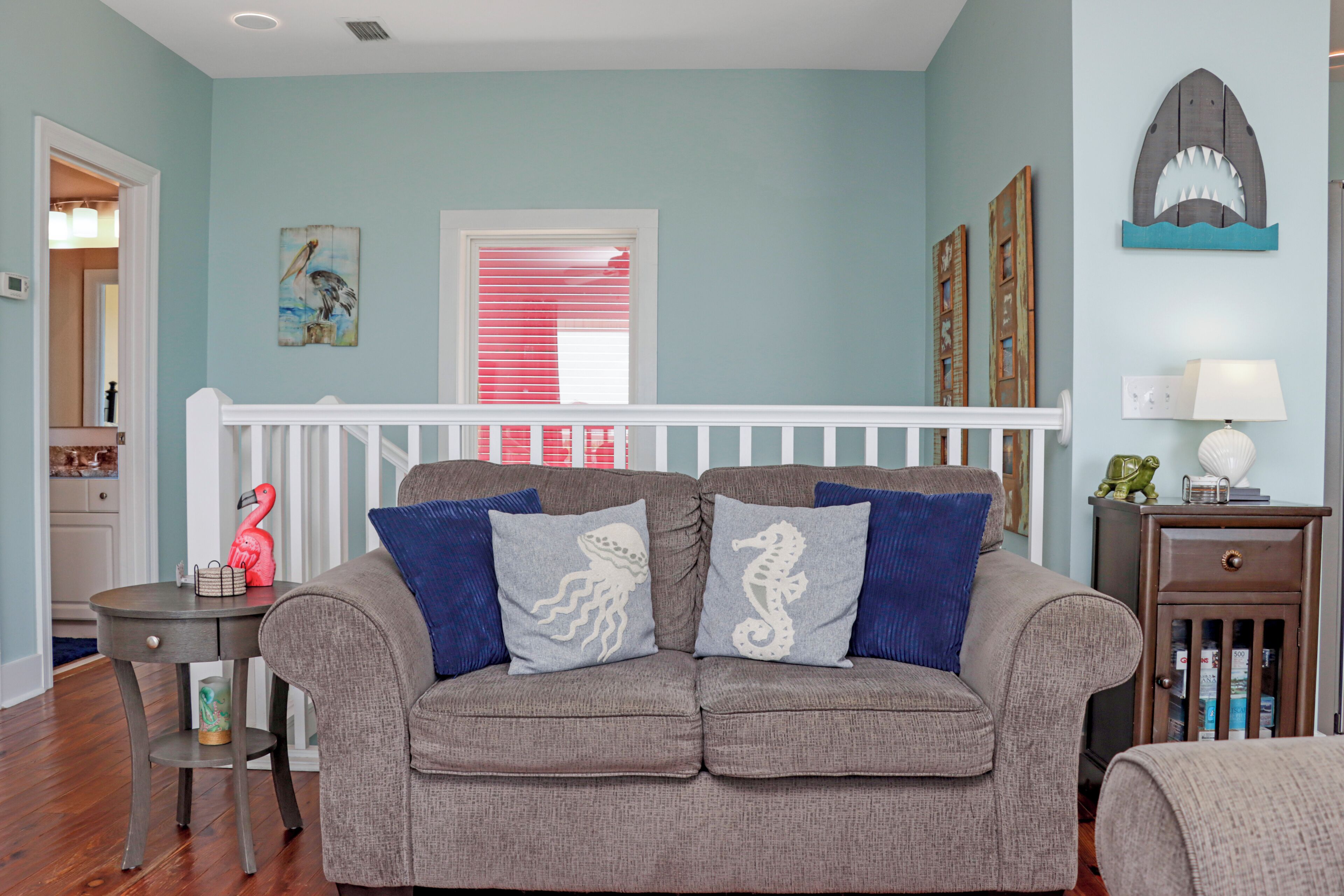 A living room with a grey sofa, blue cushions, a small table, and a wooden cabinet.