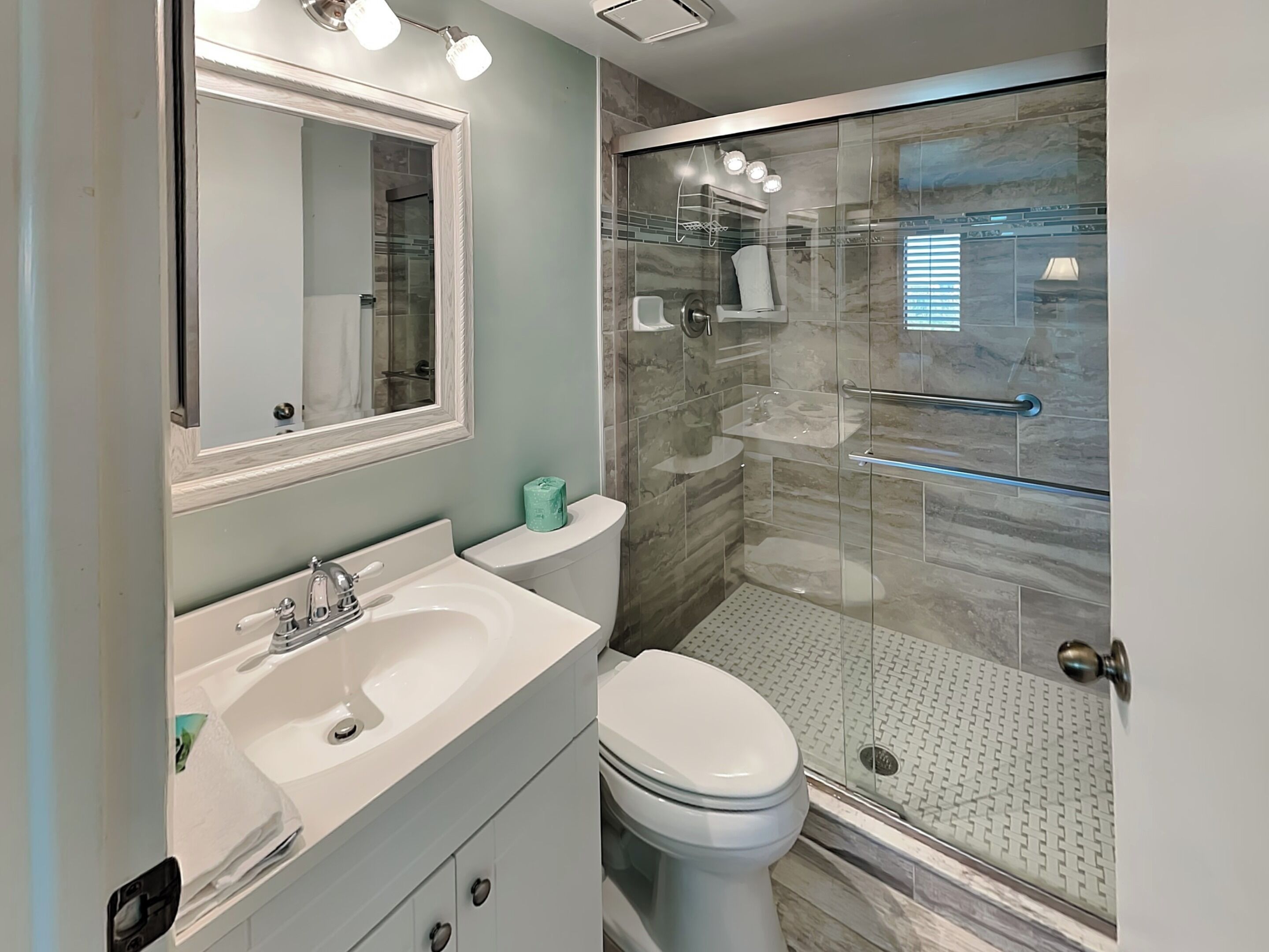 Une salle de bain moderne avec une douche à parois de verre, un lavabo blanc et des toilettes.