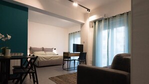 Um espaço compacto com cama, escrivaninha, cadeira e sofá.