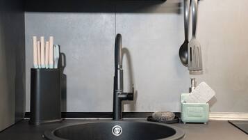 A modern kitchen sink with a faucet, a dish soap dispenser, and a utensil holder.