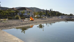 Een strand met een tent, boten en huizen op de achtergrond.