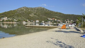 Een strand met een tent, boten en huizen op de achtergrond.