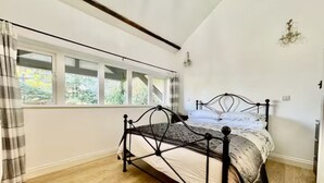 A bedroom with a bed, a window with curtains, and a chandelier.