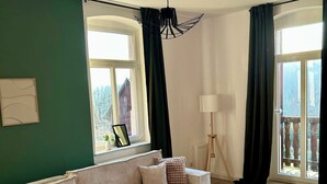 A living room with a striped sofa, a round coffee table, and a red ottoman. - HohnsteinOase-Infrared Sauna-3 Bedroom-Parking and washing machine (Hohnstein)