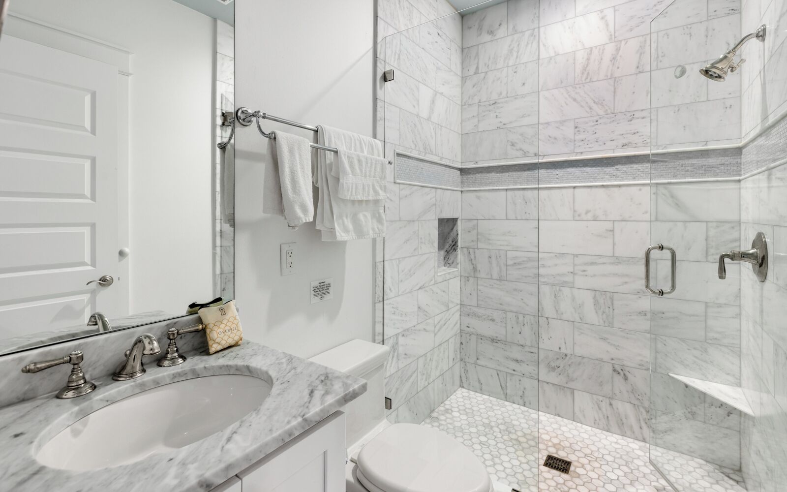 A modern bathroom with a marble sink, a toilet, and a shower area.