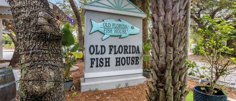 A sign for Old Florida Fish House with a fish-shaped top.