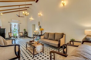 A spacious living room with a checkered floor, a sofa, and rattan chairs. - 3bhk Portuguese-style Villa w Pool Casa Aloma (Assagao)