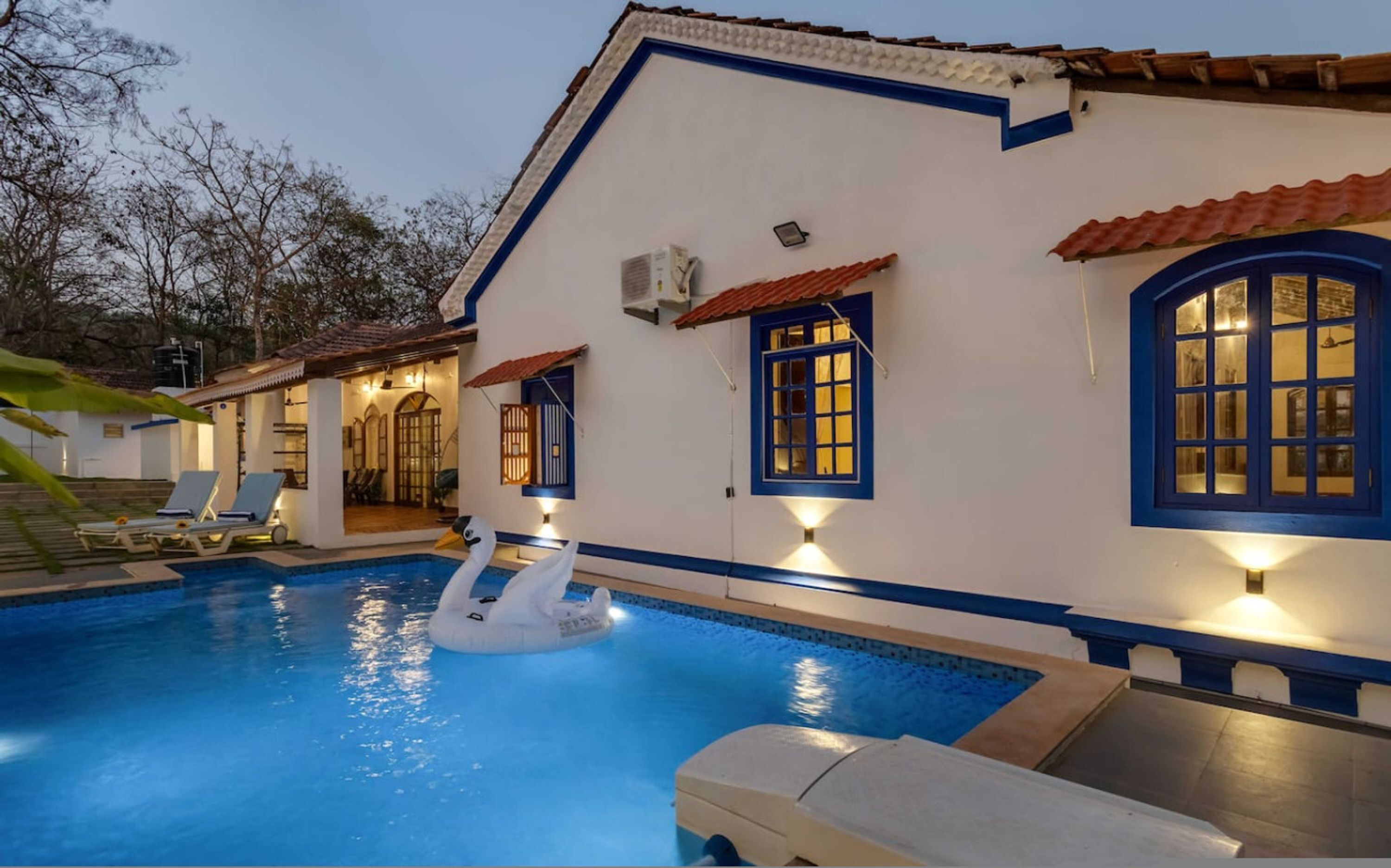 A poolside area with a white building, blue trim, and a swan float.
