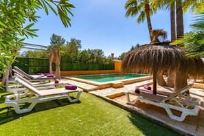 A pool area with lounge chairs and a thatched umbrella.