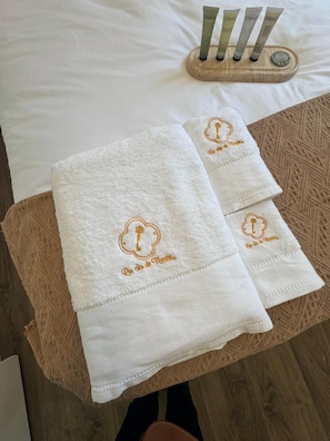 Un set di asciugamani ordinatamente disposti su un tavolo di legno, posizionato su un letto con lenzuola bianche.