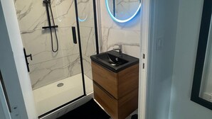 A modern bathroom with a shower, a sink, and a vanity. - Résidence de la Place (Pont-du-Château)