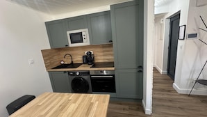 A compact kitchen with a microwave, coffee maker, and washing machine. - Résidence de la Place (Pont-du-Château)