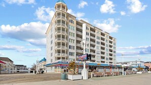A multi-story hotel with balconies, a central light fixture, and a boardwalk in front. - Belmont Towers 710 by Seaside Vacations & Sales (Ocean City)
