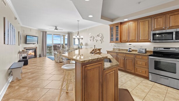 A spacious kitchen with wooden cabinets, a large island, stainless steel appliances, and a view to the outside. - Belmont Towers 710 by Seaside Vacations & Sales (Ocean City)