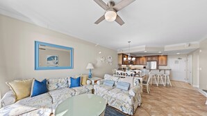 A living room with a sofa, coffee table, and a dining area with chairs and a table. - Belmont Towers 710 by Seaside Vacations & Sales (Ocean City)