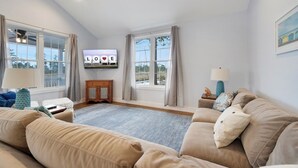 Ein Wohnzimmer mit großem Fenster, Flachbildfernseher und einer Couch.