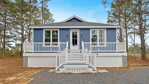 Ein zweistöckiges Haus mit Veranda, weißen Geländern und einer Auffahrt mit Kies.