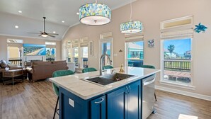 A spacious kitchen with a large island, pendant lights, and a view of the outdoors. - Nauti By Nature 3 Bedroom Home (Port Bolivar)