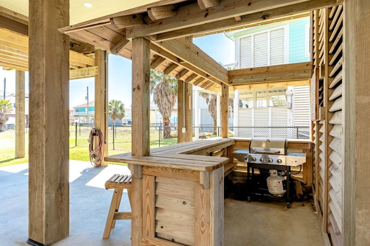Eine hölzerne Pergola im Freien mit Grillplatz, inklusive Grill und Holztisch.