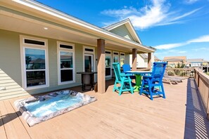 Eine überdachte Terrasse im Freien mit Whirlpool, Tisch und Stühlen sowie Blick auf den Ozean.