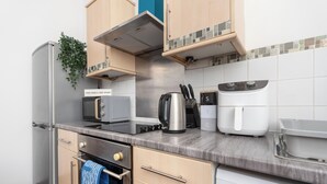 Eine moderne Küche mit Edelstahlgeräten, einer Mikrowelle, einem Wasserkocher und einer Kaffeemaschine.