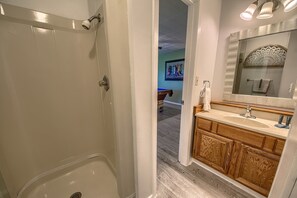 Ein Badezimmer mit Dusche, einem Holzkosmetikschrank und einem großen Spiegel.