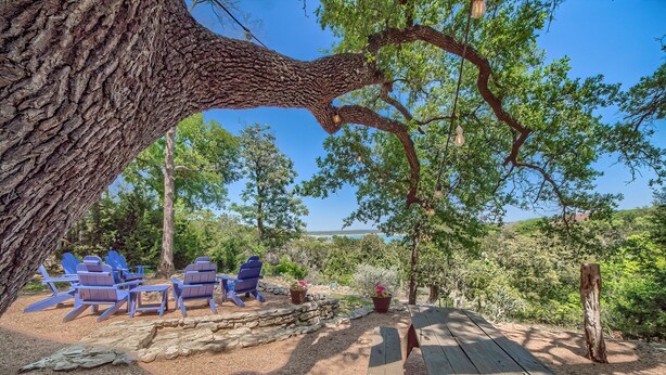A picnic area with blue chairs, a wooden table, and a stone wall.