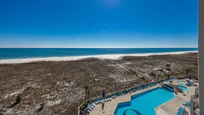 Un resort en la playa con piscina, sillas de descanso y vista al océano.