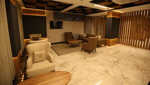 A modern lounge area with plush seating, a flat-screen TV, and a marble floor. - Büpa delüxe hotel (Kayseri)